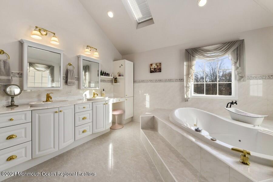 179 Stone Hill Road Colts Neck, NJ 07722 - Photo 35 of 57 a spacious bathroom with double vanity a mirror a bathtub and a sink