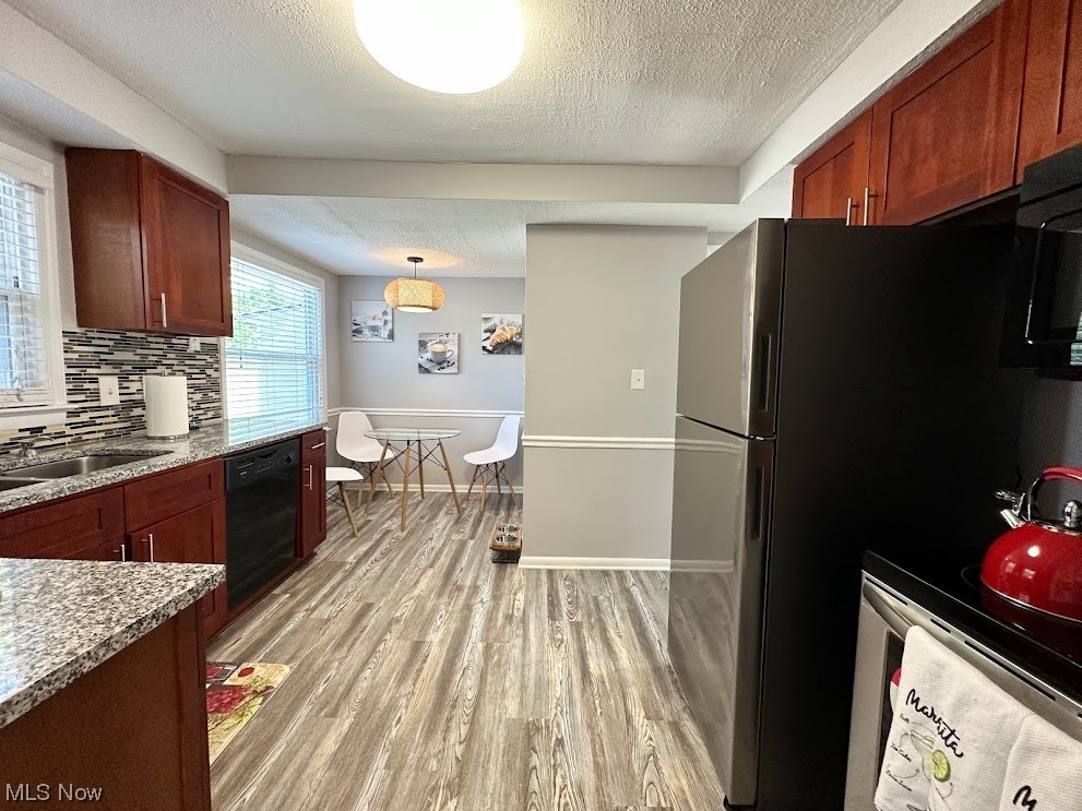 Kitchen with sink, decorative light fixtures, tasteful backsplash, and light hardwood flooring