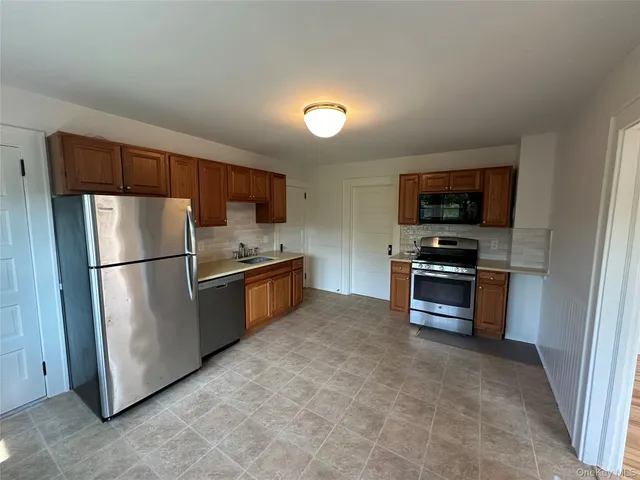 a kitchen with granite countertop a refrigerator and a stove top oven