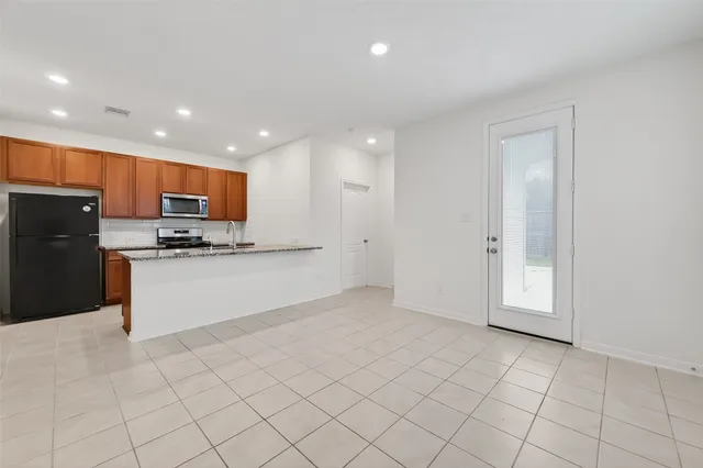 a kitchen with stainless steel appliances granite countertop a refrigerator a sink a stove a microwave and a refrigerator