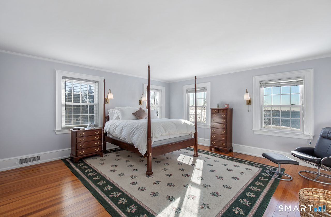 35 Point Lookout Milford, CT 06460 - Photo 20 of 31 A spacious and serene primary bedroom featuring hardwood floors, abundant natural light, and beautiful water views, creating a peaceful retreat with timeless charm and coastal appeal.