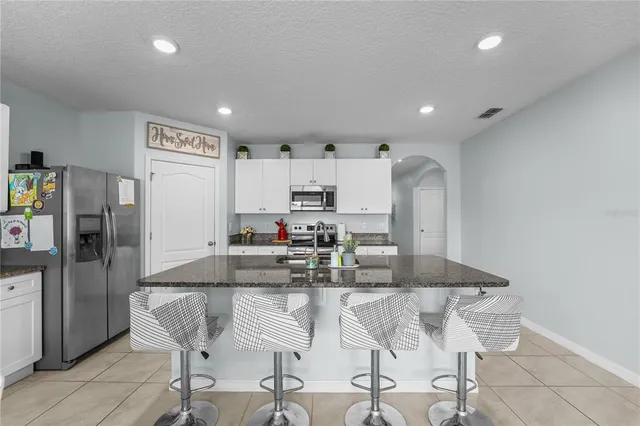 a kitchen with kitchen island granite countertop a counter space dining table and stainless steel appliances