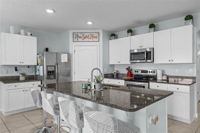 a kitchen with stainless steel appliances granite countertop a sink a stove and a refrigerator