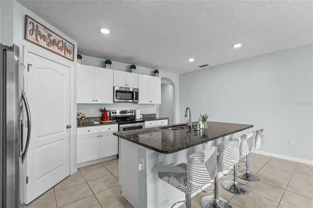 a kitchen with stainless steel appliances granite countertop a sink a stove a refrigerator a microwave and cabinets