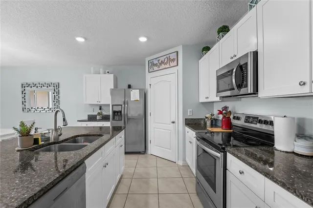 a kitchen with granite countertop a sink dishwasher stove and cabinets