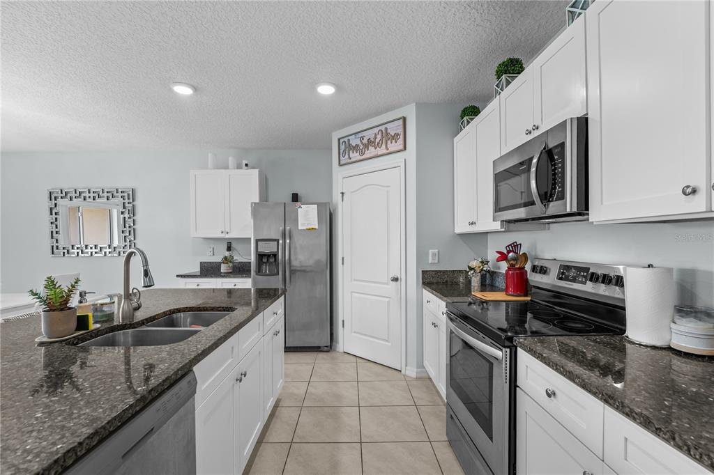 1833 Bluepoint Street St. Cloud, FL 34771 - Photo 25 of 46 a kitchen with granite countertop a sink dishwasher stove and cabinets