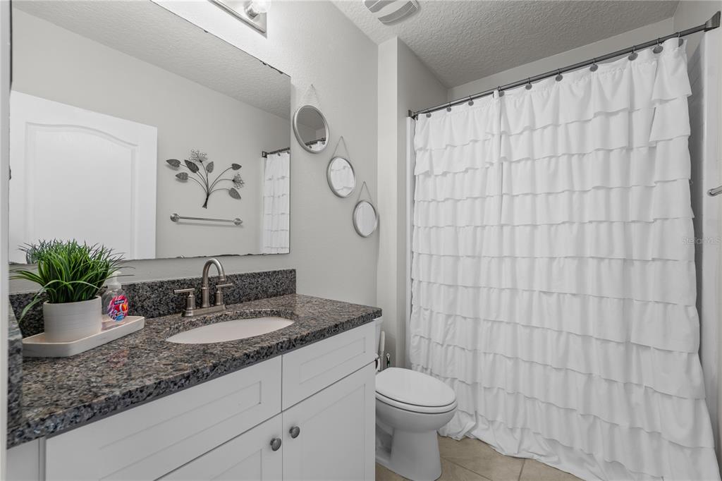 1833 Bluepoint Street St. Cloud, FL 34771 - Photo 42 of 46 a bathroom with a granite countertop sink a toilet and a mirror