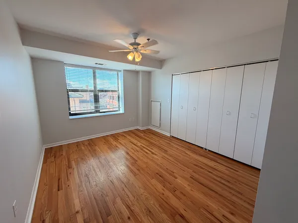 a view of an empty room with wooden floor and window