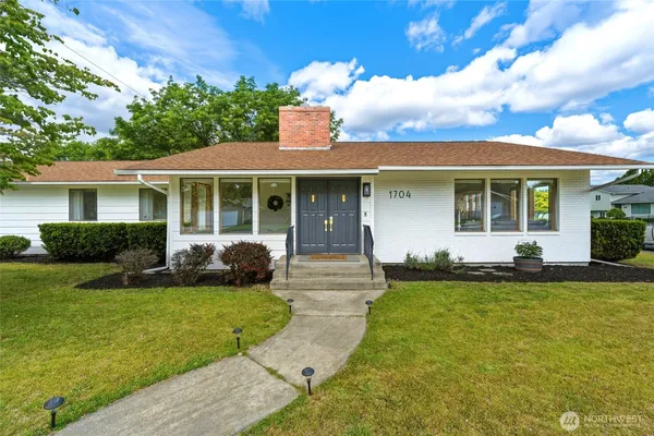 a front view of a house with a yard and potted plants