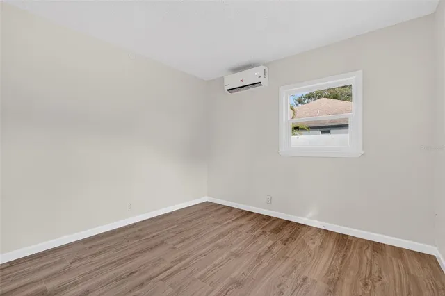 a view of an empty room with wooden floor and closet