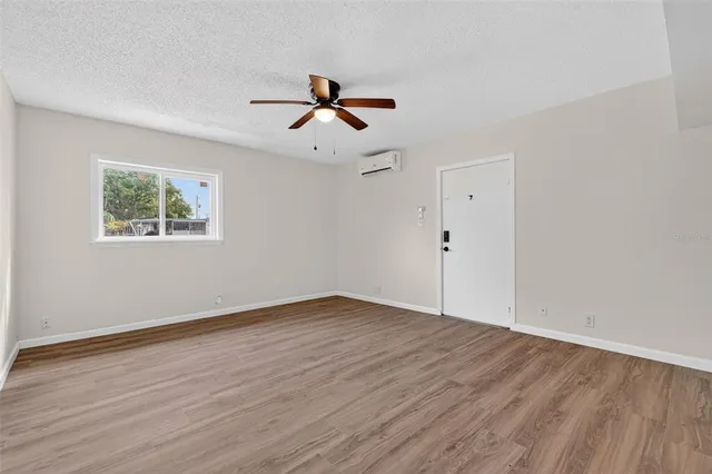a view of empty room with wooden floor and ceiling fan