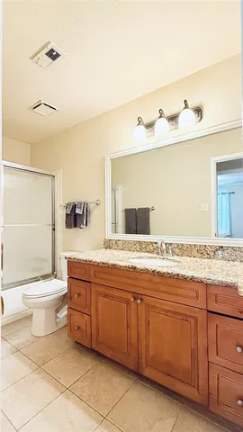 a bathroom with a granite countertop toilet sink and mirror