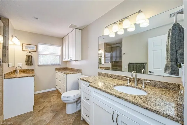 a bathroom with a granite countertop sink a toilet a mirror and vanity