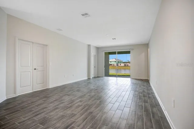 a view of an empty room and window with wooden floor