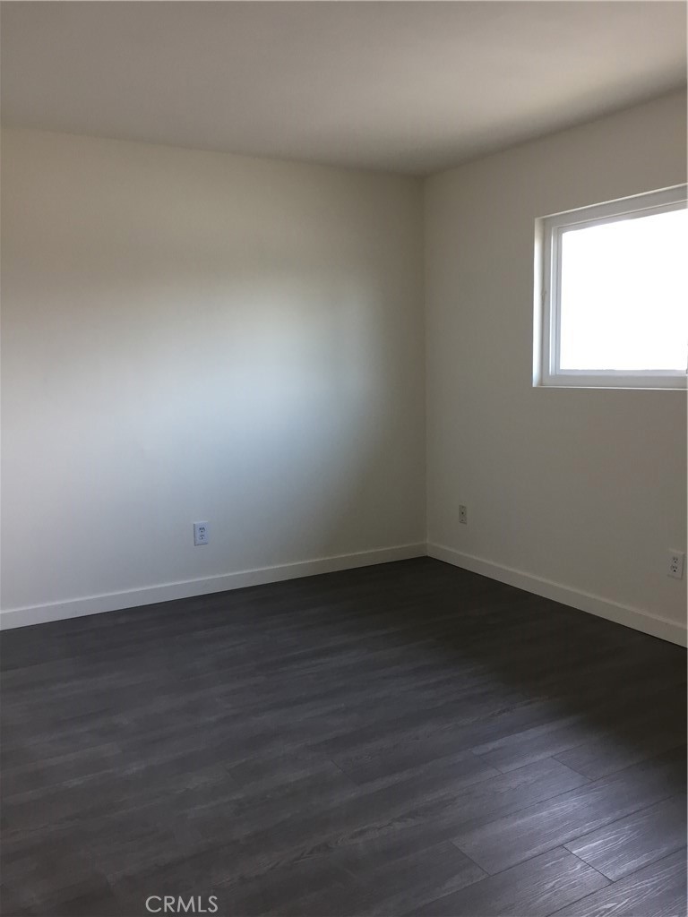 17011 Sims Lane, Unit 6 Huntington Beach, CA 92649 - Photo 7 of 19 an empty room with wooden floor and windows