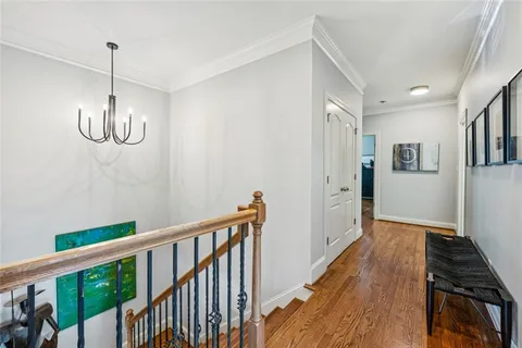 a view of a hallway with wooden floor and chandelier