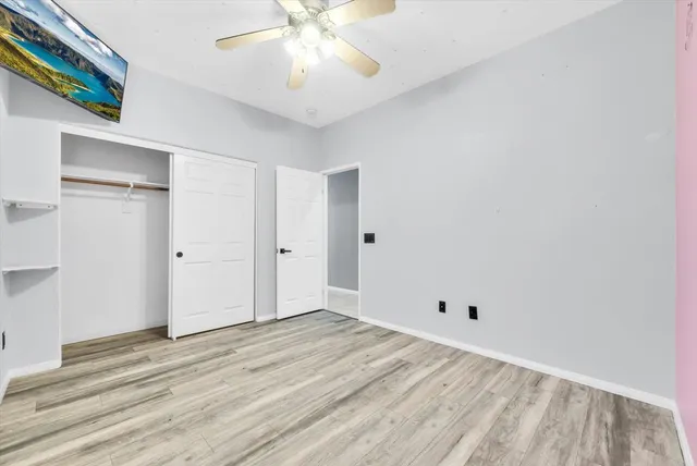 a view of a room with wooden floor and ceiling fan