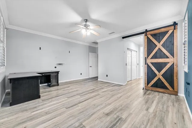 a view of empty room with wooden floor and fan