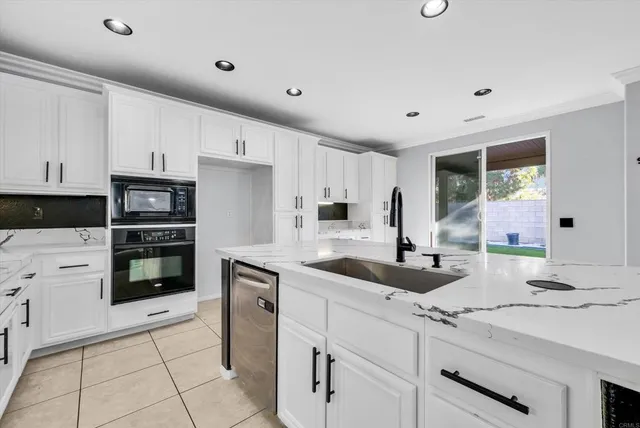 a kitchen with granite countertop a sink and white cabinets