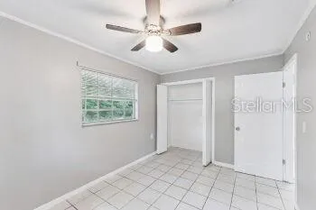 a view of an empty room with window and chandelier fan