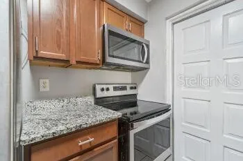 a kitchen with granite countertop cabinets stainless steel appliances and a counter space