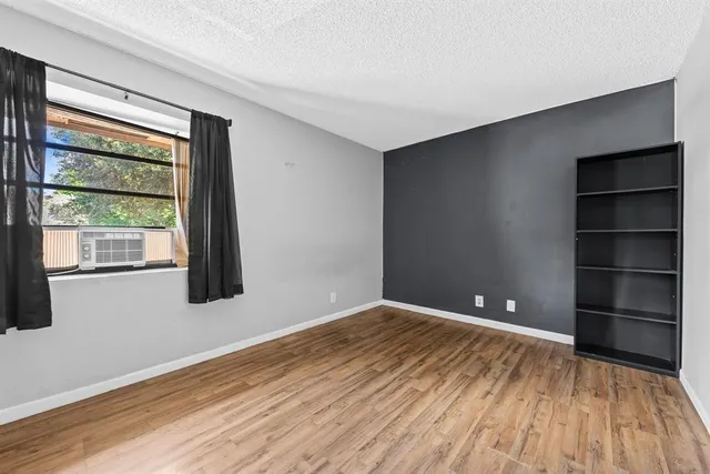 a view of an empty room with a window and wooden floor