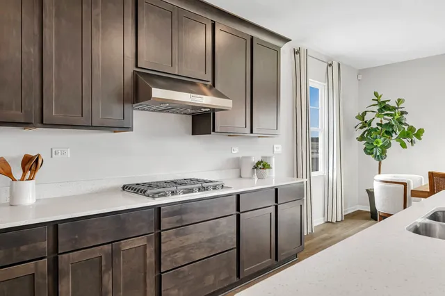 a kitchen with stainless steel appliances a sink a stove cabinets and wooden floor