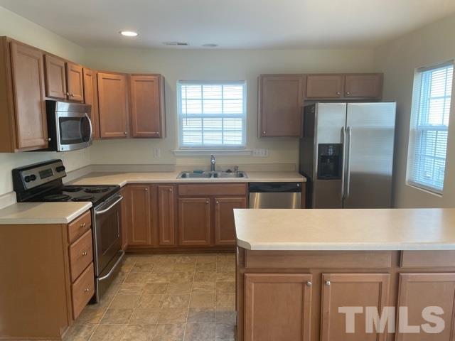7831 Averette Field Drive Raleigh, NC 27616 - Photo 9 of 20 a kitchen with a sink a stove a refrigerator a center island and a window