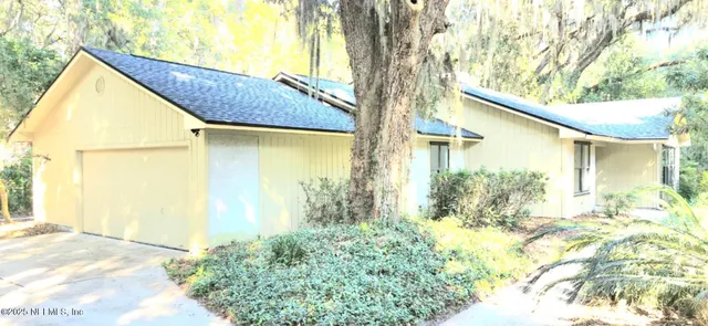 a view of yellow house with a large tree and wooden fence