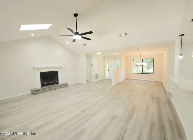 a view of an empty room with a window and a kitchen