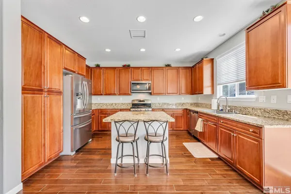 a kitchen with stainless steel appliances granite countertop wooden cabinets a sink and a refrigerator
