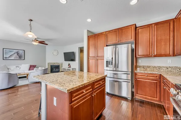 a kitchen with stainless steel appliances granite countertop a refrigerator a sink dishwasher a stove with wooden floor and cabinets