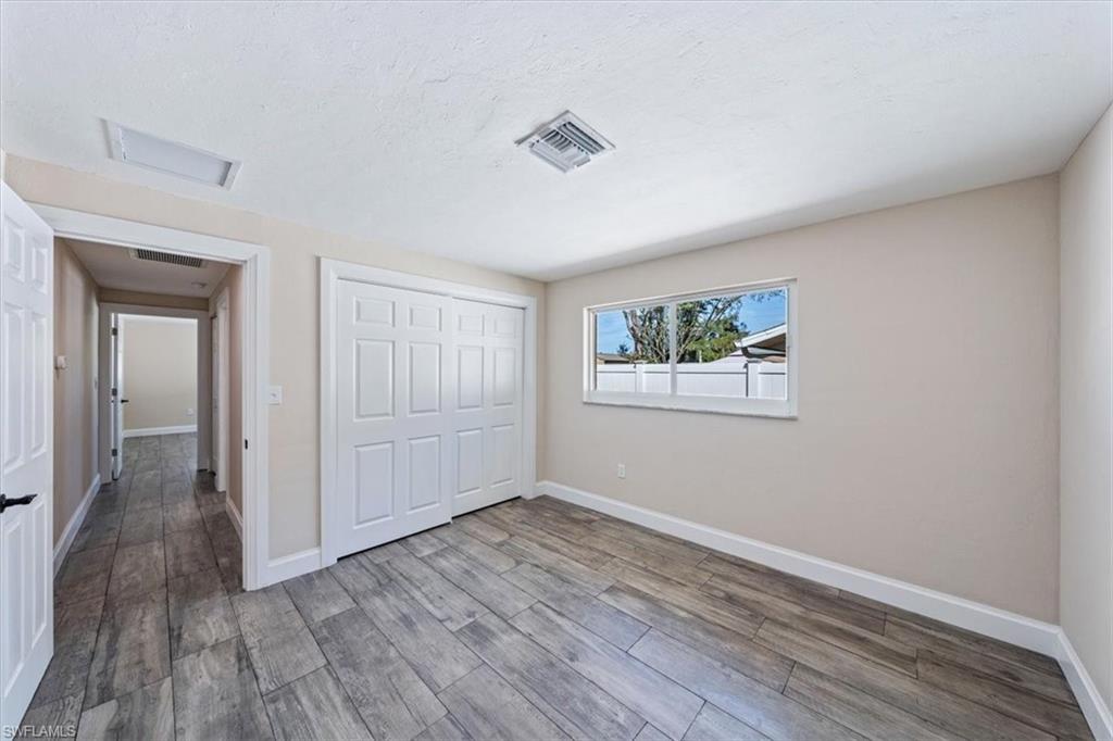 2545 Dawn Circle Naples, FL 34103 - Photo 13 of 20 a view of an empty room with wooden floor and a window