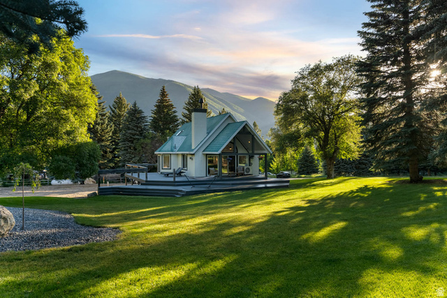 10686 South Covered Brg Cyn Road, Unit 14 Spanish Fork, UT 84660 - Photo 1 of 44 Gable-roofed home featuring a substantial wood deck, expansive lawn, and mature trees, set against a mountainous backdrop