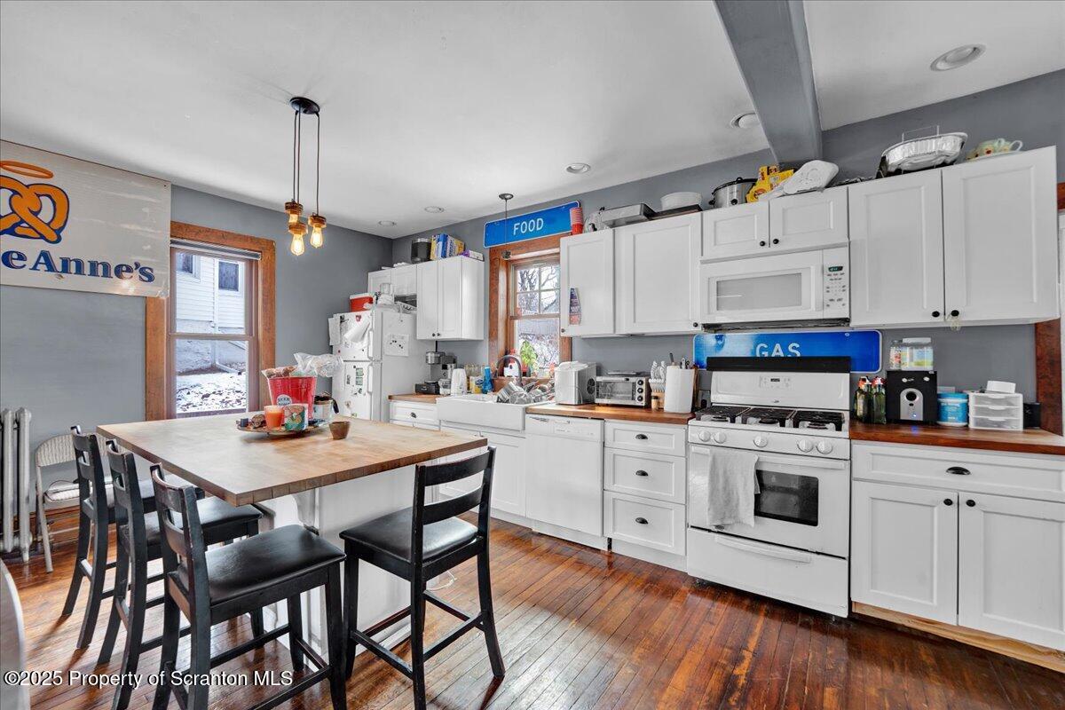 Undisclosed Address Scranton, PA 18509 - Photo 6 of 26 a kitchen with a stove a sink dishwasher white refrigerator a dining table and chairs with wooden floor