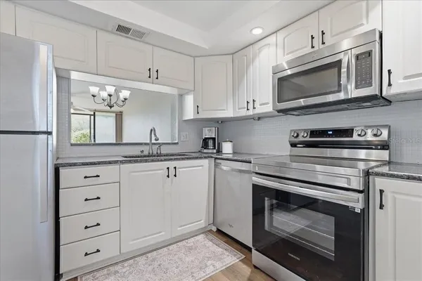 a kitchen with white cabinets and refrigerator