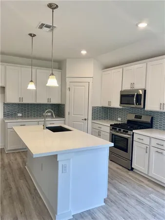 a large kitchen with stainless steel appliances kitchen island a cabinets and wooden floor