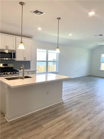 a kitchen with stainless steel appliances granite countertop a sink a window and a wooden floor