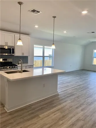 a kitchen with stainless steel appliances granite countertop a sink a window and a wooden floor