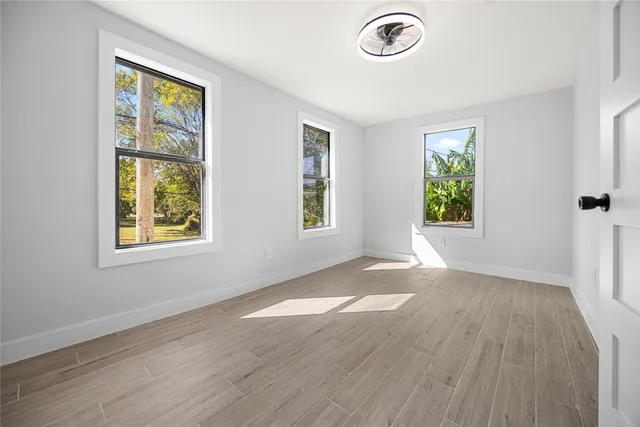 a view of an empty room with a window and wooden floor