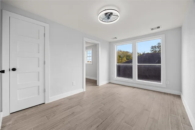 an empty room with wooden floor and windows
