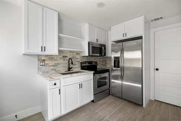 a kitchen with a refrigerator a microwave a sink and cabinets