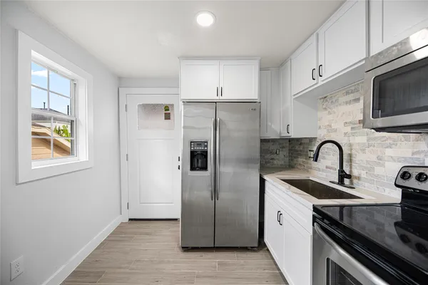 a kitchen with stainless steel appliances granite countertop a refrigerator a sink a stove a microwave and cabinets