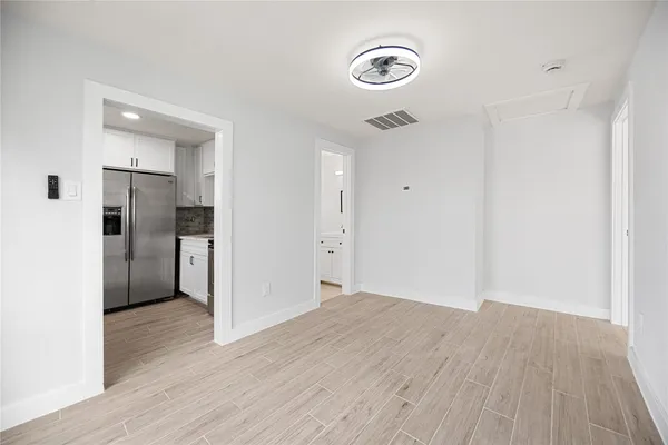 a view of a kitchen with a fridge and wooden floor