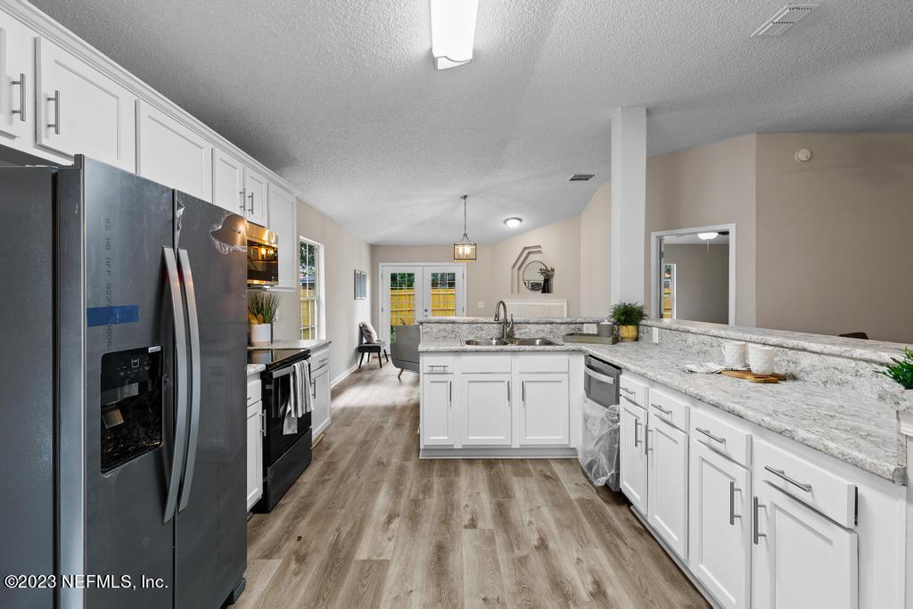 1652 Spring Oaks Lane Jacksonville, FL 32221 - Photo 15 of 37 a large kitchen with a refrigerator a sink dishwasher a stove and white cabinets with wooden floor