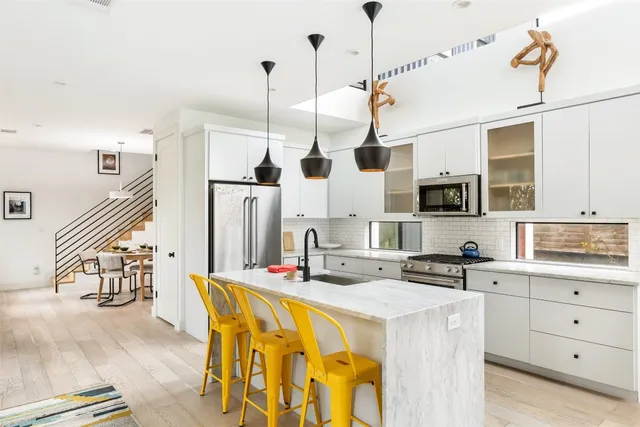 a kitchen with stainless steel appliances kitchen island granite countertop a sink a stove and a wooden floors