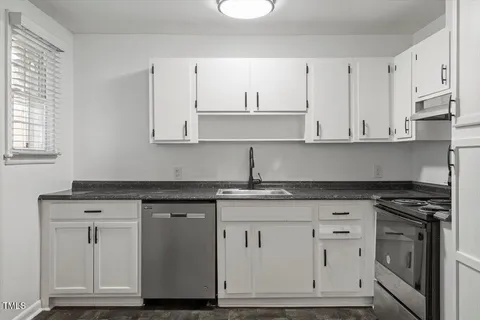 a kitchen with granite countertop white cabinets and a stove