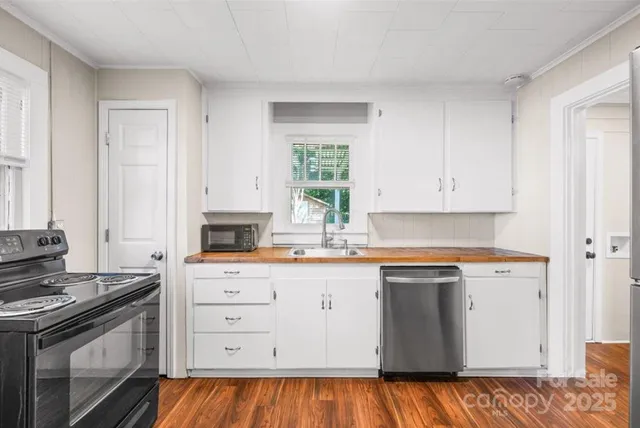 a kitchen with granite countertop a stove a sink and white cabinets