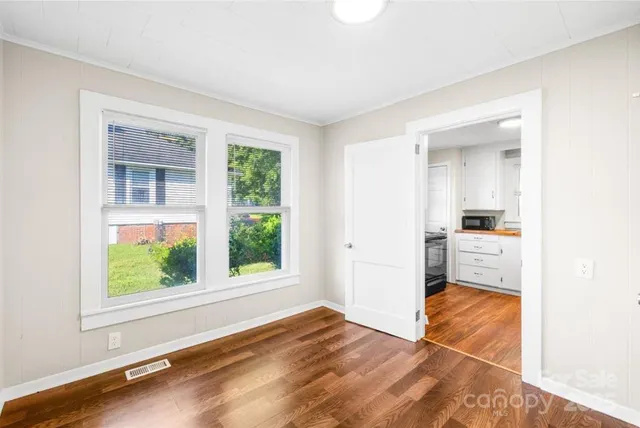 a view of an empty room with window and wooden floor