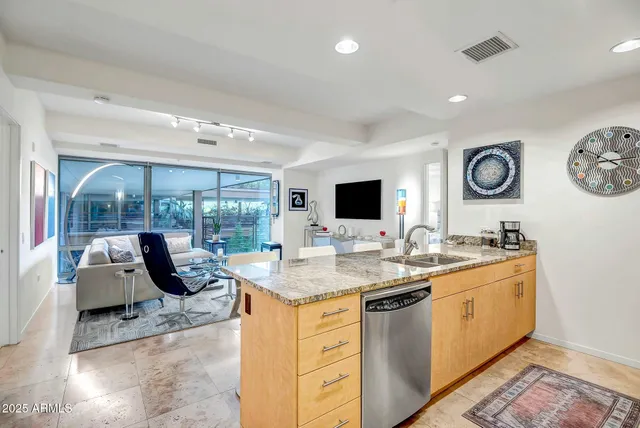 a view of a kitchen with kitchen island granite countertop a sink and a stove top oven with wooden floor